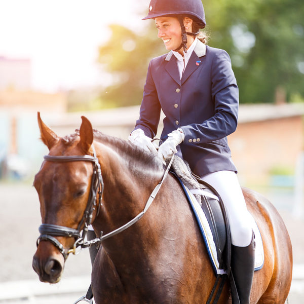 Young happy woman on her horse after dressage test Young happy woman on her bay horse after dressage test on equestrian competitions 