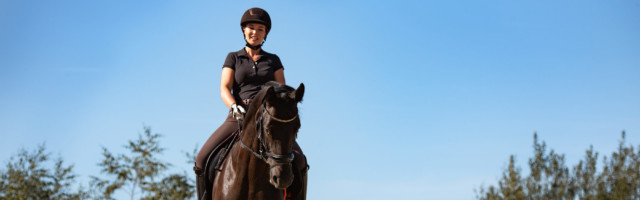Reiterin reitet Seitengänge mit ihrem Pferd im Sommer auf einem Reitplatz 