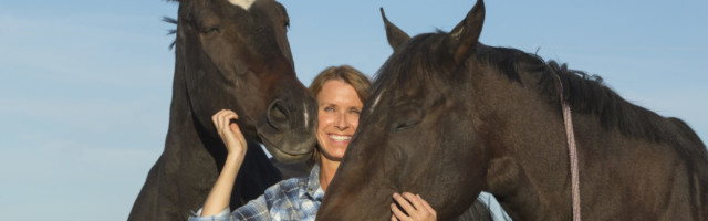 Caucasian rancher smiling with horses Caucasian rancher smiling with horses 