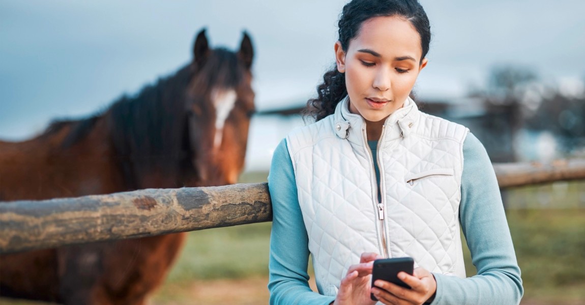 I cant wait to post this. an attractive woman using her cellphone while posing with a horse in an enclosed pasture on a farm. an attractive woman using her cellphone while posing with a horse in an enclosed pasture on a farm. 