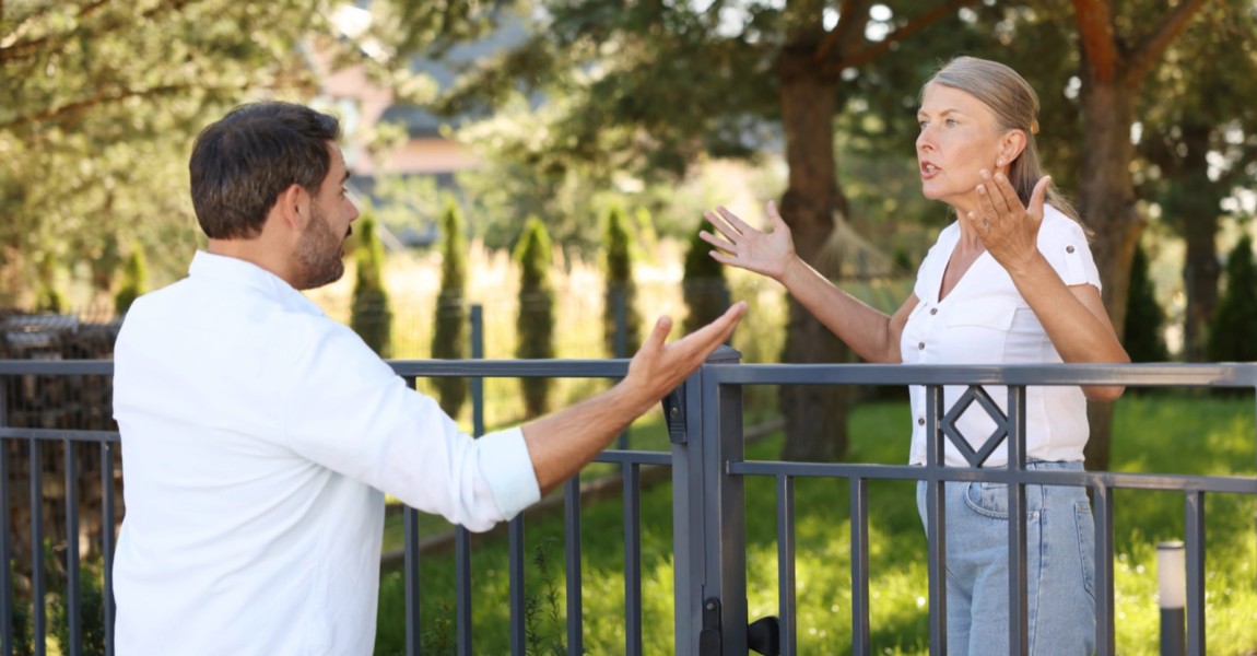 Emotional neighbours having argument near fence outdoors Emotional neighbours having argument near fence outdoors 